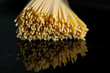 Italian pasta spaghetti noodles on reflecting black background surface raw ingredient for recipe 