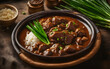Filipino adobo, savory sauce, green onions, ceramic plate, warm kitchen setting
