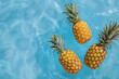 Three pineapples falling into the water of a pool illuminated by the sun. Summertime concept.