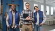 © VAKSMANV - View of three multi-ethnic people smiling with joy while looking directly at camera. Handsome manager with clipboard standing between two engineers of manufacturing factory. Enjoying their work.