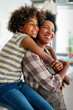 © NDABCREATIVITY - African american woman hugging her smiling teen daughter. Family love single parent child concept