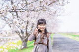 Fototapeta  - 桜の木の下でピースをする女の子