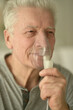 Close-up portrait of an elder man making inhalation