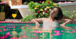 Indian Asian Hindu relax woman bathing rose petals water park pool edge resort hold glass drink fresh juice outdoor home happy young adult female girl luxury hotel villa trip do pose enjoy fun joy day