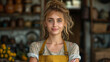 Portrait of a young female entrepreneur with blonde hair and blue eyes, wearing a casual apron, standing confidently in a rustic kitchen setting with shelves of pottery in the background.