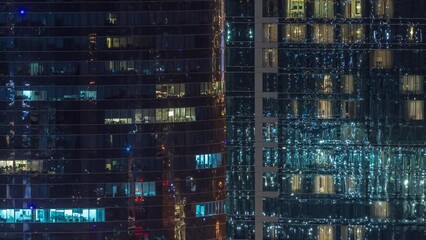 Canvas Print - Office and residential buildings windows illuminated at night timelapse. Glass architecture, corporate building at evening with glowing lights. Reflections on skyscrapers surface