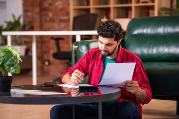 Indian man is busy in accounting at home sitting in living room