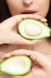 Avocado in hands of young woman in nature close-up
