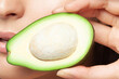 Close-up of avocado cut in half in woman's hand