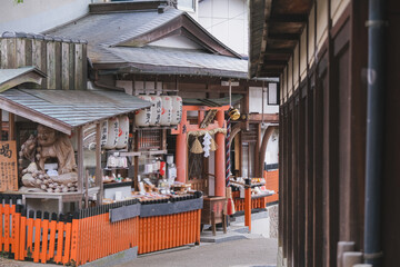 Red pagodas and gates up the mountain in Fushimi Inari-Taisha shinto shrine temple in Kyoto, Japan with traditional architecture buildings, buddha and fox statues decorations and Japanese garden