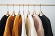 © Carlos Dominique - A row of clothes hanging on a clothesline, including a black sweater, a yellow sweater, a white sweater, and a pink sweater