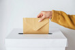 Close-up female hand putting voting card into the ballot box. Vote on free democratic elections or referendum.