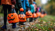 Closeup of children with hands holding pumpkins bags playing trick or treat outdoors.
