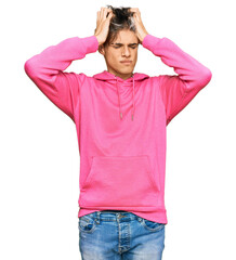 Canvas Print - Young hispanic man wearing casual pink sweatshirt suffering from headache desperate and stressed because pain and migraine. hands on head.