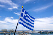 Greek national flag fluttering in the wind at sea harbor