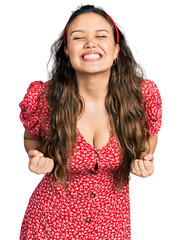 Poster - Young hispanic girl wearing casual clothes excited for success with arms raised and eyes closed celebrating victory smiling. winner concept.