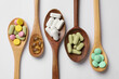 Different vitamin pills in wooden spoons on white background, flat lay