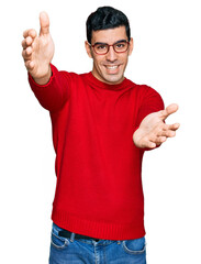 Wall Mural - Handsome hispanic man wearing casual clothes and glasses looking at the camera smiling with open arms for hug. cheerful expression embracing happiness.