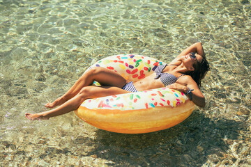 Canvas Print - Woman Laying on Inflatable Donut in Water