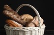 Wicker basket with different types of fresh bread on black table