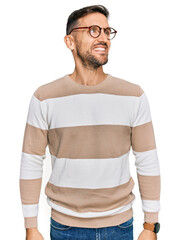 Poster - Handsome man with beard wearing casual clothes and glasses looking away to side with smile on face, natural expression. laughing confident.