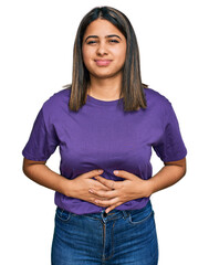 Sticker - Young hispanic girl wearing casual purple t shirt with hand on stomach because indigestion, painful illness feeling unwell. ache concept.