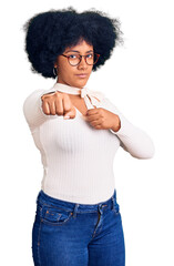 Canvas Print - Young african american girl wearing casual clothes and glasses punching fist to fight, aggressive and angry attack, threat and violence