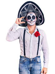 Poster - Man wearing day of the dead costume over background smiling and confident gesturing with hand doing small size sign with fingers looking and the camera. measure concept.