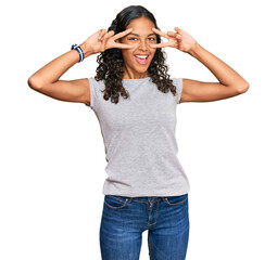 Poster - Young african american girl wearing casual clothes doing peace symbol with fingers over face, smiling cheerful showing victory