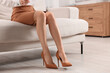 © New Africa - Woman in high heeled shoes on sofa at home, closeup