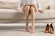© New Africa - Barefoot woman resting after wearing high heels on sofa at home, closeup