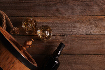 Canvas Print - Whiskey with ice cubes in glasses, bottle and barrel on wooden table, flat lay. Space for text