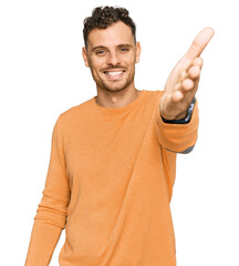 Canvas Print - Young hispanic man wearing casual clothes smiling friendly offering handshake as greeting and welcoming. successful business.