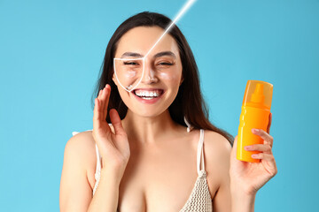 Sticker - Young woman with sunscreen cream on blue background