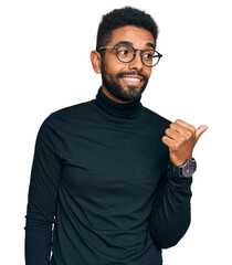 Sticker - Young african american man wearing casual clothes smiling with happy face looking and pointing to the side with thumb up.