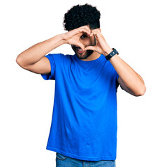 Poster - Young arab man with beard wearing casual blue t shirt doing heart shape with hand and fingers smiling looking through sign