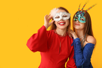 Poster - Happy young women in carnival masks on yellow background