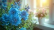   A window sill hosts several blue blooms alongside a potted plant, facing a window