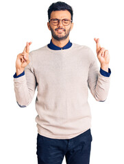 Wall Mural - Young handsome hispanic man wearing elegant clothes and glasses gesturing finger crossed smiling with hope and eyes closed. luck and superstitious concept.