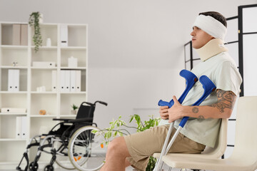 Poster - Injured young man after accident with crutches waiting for his turn in clinic