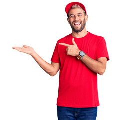 Sticker - Young handsome blond man wearing t-shirt and cap amazed and smiling to the camera while presenting with hand and pointing with finger.