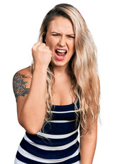 Canvas Print - Young blonde woman wearing casual clothes angry and mad raising fist frustrated and furious while shouting with anger. rage and aggressive concept.