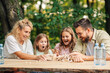 © Zamrznuti tonovi - A cheerful family is playing fun jenga game in nature at the table.