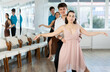 © JackF - Expressive Hispanic guy in formal attire practicing sensual bachata with attractive young brunette in light flowing dress in dance class. Social dancing concept..