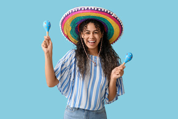 Poster - Happy young African-American woman in sombrero hat with maracas on blue background