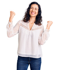 Wall Mural - Young beautiful hispanic woman wearing casual clothes very happy and excited doing winner gesture with arms raised, smiling and screaming for success. celebration concept.