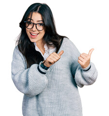 Sticker - Beautiful hispanic woman wearing casual sweater and glasses pointing to the back behind with hand and thumbs up, smiling confident