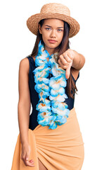 Canvas Print - Young beautiful latin girl wearing hawaiian lei and summer hat looking unhappy and angry showing rejection and negative with thumbs down gesture. bad expression.