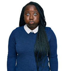 Wall Mural - Young black woman with braids wearing casual clothes puffing cheeks with funny face. mouth inflated with air, crazy expression.