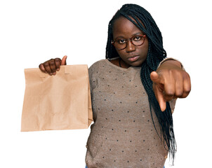 Poster - Young black woman with braids holding take away paper bag pointing with finger to the camera and to you, confident gesture looking serious